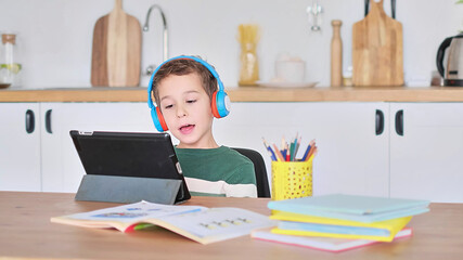 Smart boy student listen to online lesson on tablet wear headphones Spbas. Homeschooled child watch.