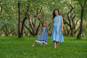 Fototapeta premium mother and child having fun in the park. Mother and little daughter playing together in a park. Happy family concept.