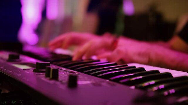 Musicians playing at a wedding. Man is playing synthesizer. Stage lights