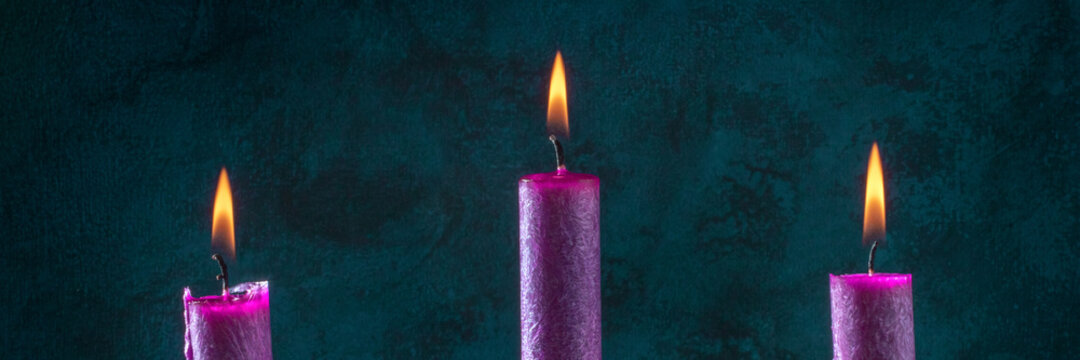 Candle panorama with burning purple candles on a dark blue background