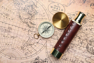 Fototapeta na wymiar Old spyglass and compass on vintage world map