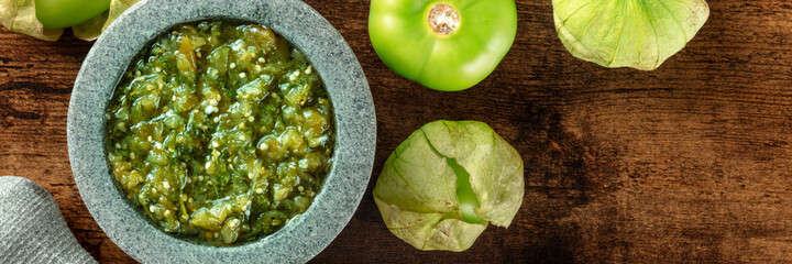 Tomatillos, green tomatoes, and salsa verde, green sauce, panorama with a molcajete, traditional...