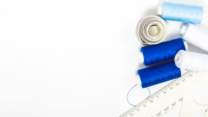 Tailor's desk. sewing tools. Natural fabric. Blue cloth, threads, spools, scissors on a white background