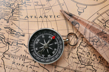 Old compass and paper airplane on vintage world map