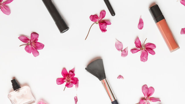 Decorative flat lay composition with makeup products, cosmetics and flowers. Flat lay, top view on white background.