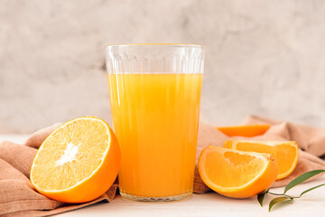 Glass with tasty orange juice on light background