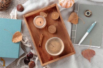 Hygge. Autumn still life with coffee, candles, fall leaves, a journal, and some books, overhead flat lay shot