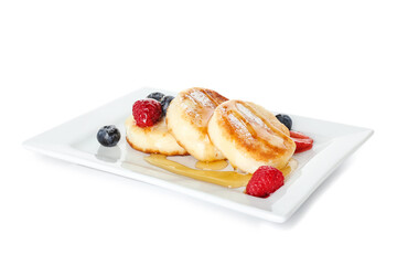 Plate with tasty cottage cheese pancakes, berries and honey on white background