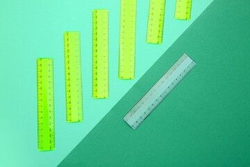 Transparent ruler among green ones on color background. Concept of uniqueness