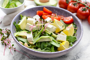Plate with healthy salad with feta cheese on light background