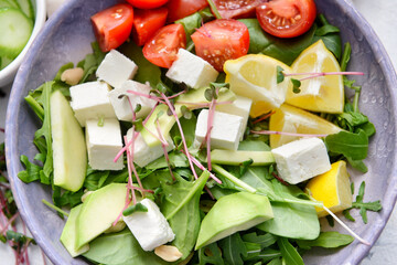 Plate with healthy salad with feta cheese on light background