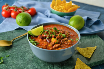 Bowl with delicious chili con carne and lime on table