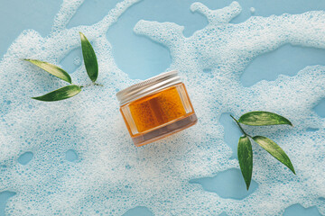 Composition with jar of cosmetic product and foam on color background