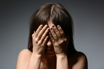 Stressed young woman on grey background. Concept of harassment
