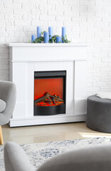 Modern fireplace with candles near brick wall