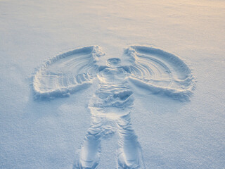Snow angel made in the white snow in the evening.