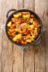 Chinese Galinha a Portuguesa chicken stew with vegetables in coconut curry close-up in a frying pan on the table. Vertical top view from above
