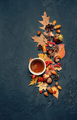Tea cup, acorns, leaves, nuts, cones on dark background. Autumn tea party. symbol of fall time,...
