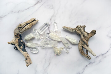 set of clear quartz minerals and tree branch on marble  background. gemstones crystals for esoteric...
