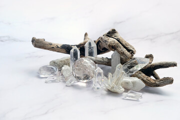 set of clear quartz minerals and dry tree branch on abstract marble  background. gemstones crystals...