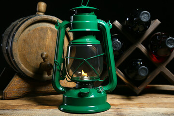Stylish retro lamp and stand with bottles of wine on wooden table