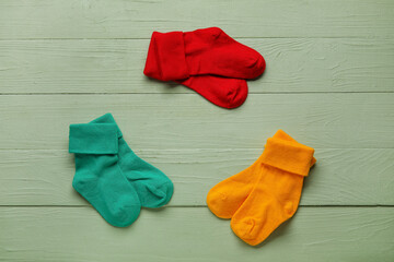 Different baby socks on color wooden background