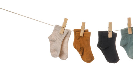 Different baby socks hanging on rope against white background