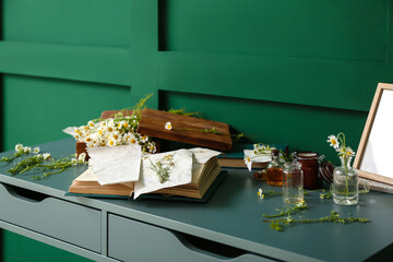 Book with dried chamomiles on table