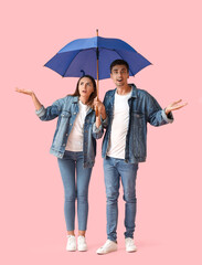 Young couple with umbrella on color background