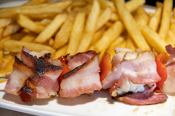 brochette de poulet lardé et frites dans une assiette