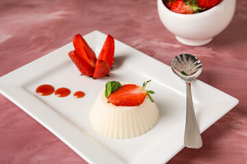 Plate with delicious strawberry panna cotta dessert on color background