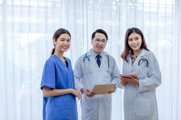 Successful team of medical doctors are looking at camera and smiling while standing in hospital