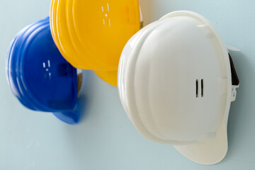 Plastic hardhats hanging on color wall