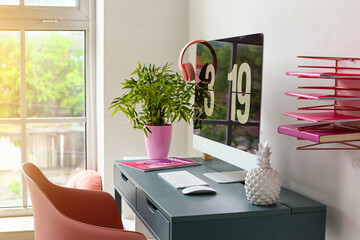 Stylish workplace with modern computer, magazine and decor near window on sunny day