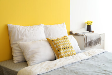 Soft pillows on big bed near color wall