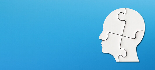 Head made of white jigsaw puzzle four pieces with copy space on blue background