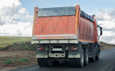 dump truck moves along a country road.