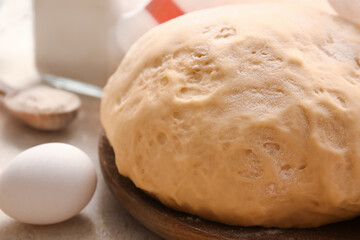 Wooden board with fresh dough on table, closeup