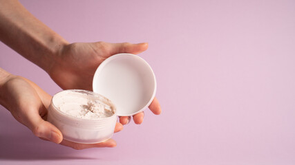 Cosmetic face mask on purple background. Pink facial mask cream. White skin care advertising image