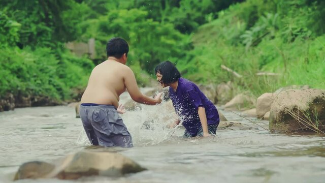 Children playing with friends in the river in countryside, Boys and girls smiling and happiness playing water in the countryside in Thailand.