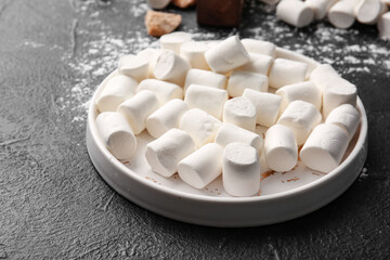 Fototapeta na wymiar Plate with tasty marshmallows on dark background