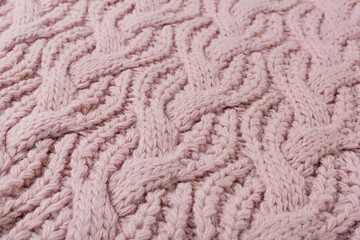 chunky knit fabric with large diagonal patterns, pastel pink, selective focus, macro