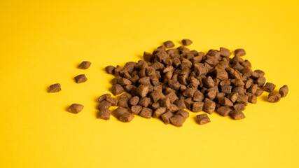Heap of cat food. Cat meal isolated on yellow background. Cat food portion on golden background