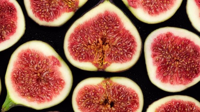 Figs. Sliced fresh figs top view, rotate. Figs Isolated on black Background. 4K UHD video 