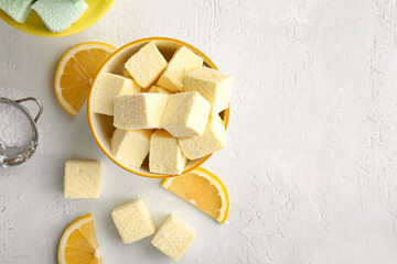 Bowl with tasty sweet marshmallows and orange on light background
