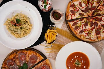 Italian cuisine composition, pasta, pizza, tiramisu and panna cotta. Top view. 