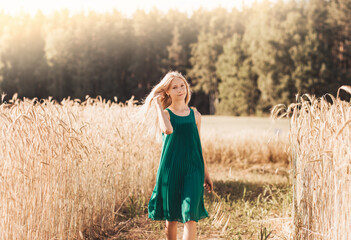 Beautiful teenage girl with long white hair walking through a wheat field on a sunny day