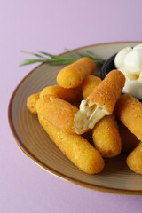 Plate with cheese sticks, mozzarella and rosemary on violet background
