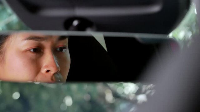 The view from the rearview mirror of stressed woman and tired exhausted crying in the car. Overworked driver concept.