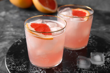 Glasses of tasty grapefruit margarita on grunge background